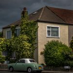 green and white coupe parked outside the house