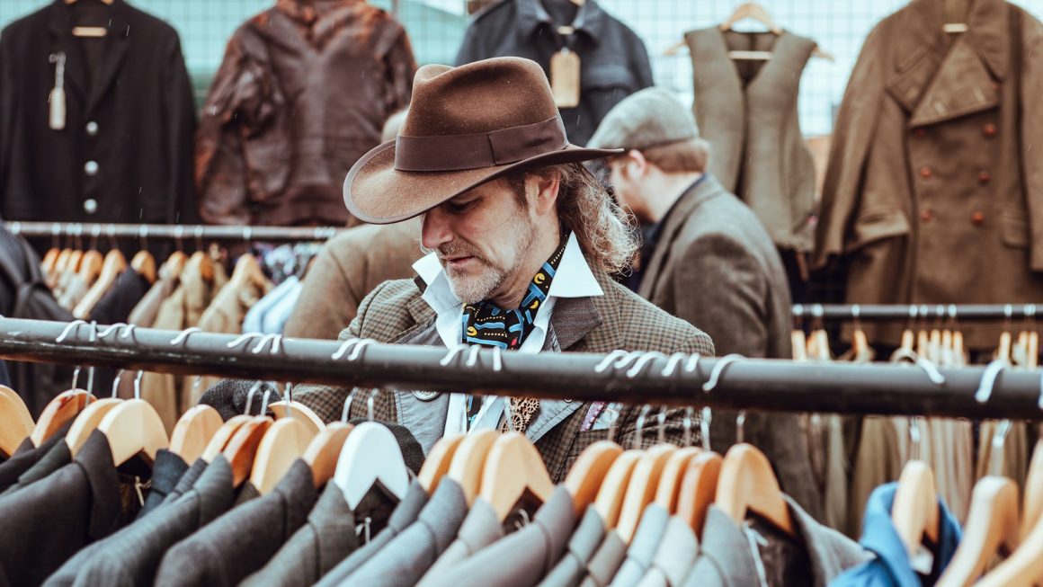 man in brown cowboy hat in front of hanged suit jackets