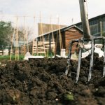 a garden fork stuck in a pile of dirt